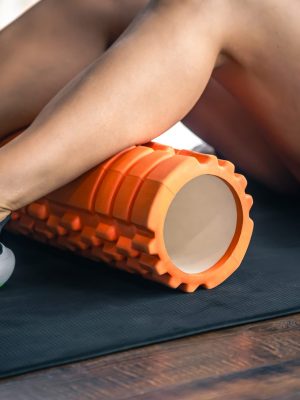 A young caucasian woman sportswoman uses a foam roller massager for relaxation, stretching muscles.